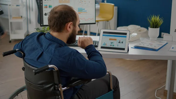 Gestionnaire paralysé homme utilisant l'ordinateur et la tablette en même temps — Photo