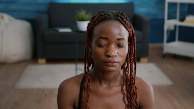 Nilüfer pozisyonunda oturup vücut kaslarını geren fit zenci kadın portresi.