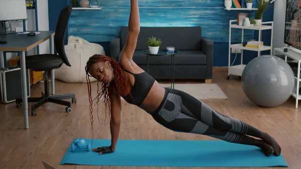 Flessibile donna nera riscaldamento sulla mappa yoga in soggiorno in piedi in tavola laterale — Foto Stock