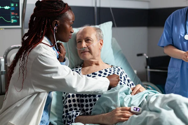Afrikanischer Kardiologe untersucht Herz eines älteren Patienten — Stockfoto
