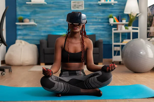 Donna nera che sperimenta la realtà virtuale formazione corpo e mente meditando in posa di loto — Foto Stock