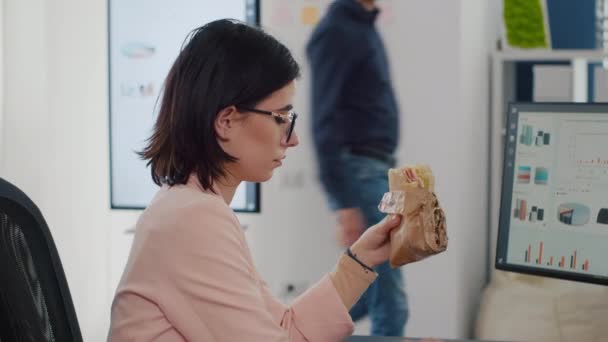 Imprenditore donna mangiare gustoso panino avendo pausa pranzo di lavoro in azienda — Video Stock