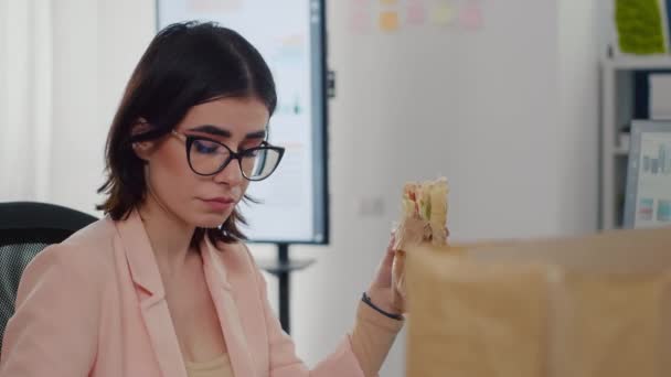 Предприниматель женщина ест вкусный бутерброд, имея перерыв на работу в бизнес-компании — стоковое видео