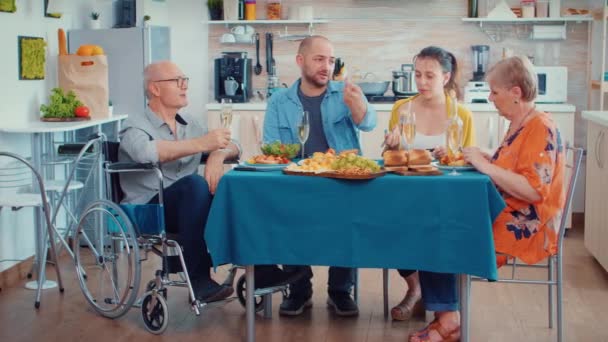 Дедушка с ограниченными возможностями и семья ужинают — стоковое видео