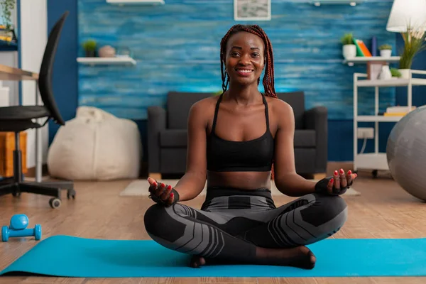 Adatta donna nera che pratica yoga seduta con le gambe incrociate — Foto Stock