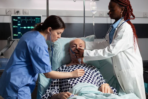 African doctor and medical assistant helping senior man breath — Stock Photo, Image