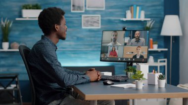 İnternet konferansında iş arkadaşlarıyla sohbet eden Afrikalı Amerikalı bir adam.