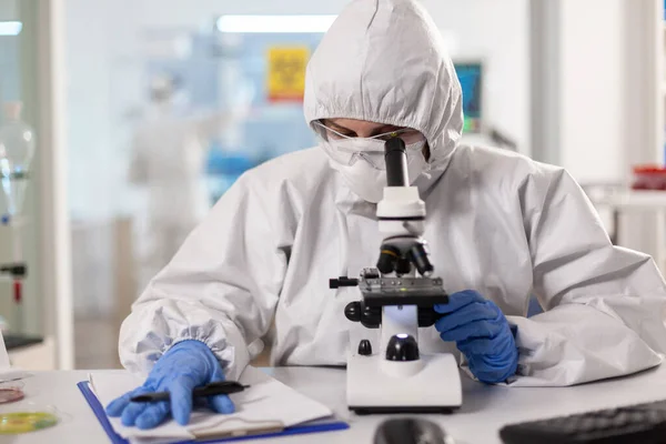 Ученый, работающий над открытием вирусной вакцины одетый в костюм ppe — стоковое фото