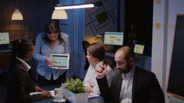 Çok çalışan işkolik girişimci kadın tablet kullanarak pazarlama grafikleri çiziyor.