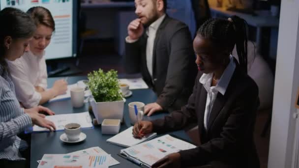 Retrato de una mujer afroamericana enfocada escribiendo estrategia de inversión en horas extras de trabajo de cuaderno — Vídeo de stock