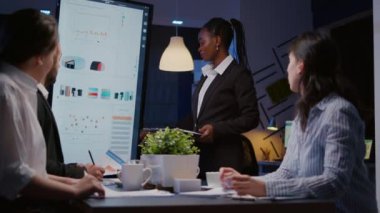 Koyu tenli iş kadını sunum monitörü kullanarak finansal grafikleri açıklıyor