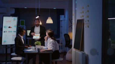 İşkolik aşırı çalışan işadamı, sunum için tablet kullanarak şirket stratejisini açıklıyor