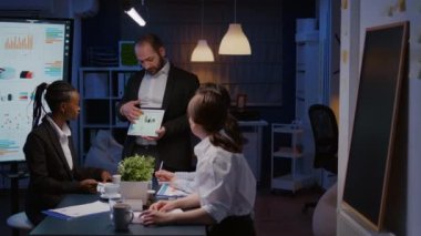Tablet kullanarak finansal grafikleri gösteren çok çalışan iş adamı