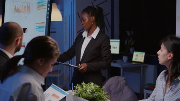 Líder afro-americano viciado em trabalho em pé na frente do monitor de apresentação explicando projeto de marketing — Vídeo de Stock