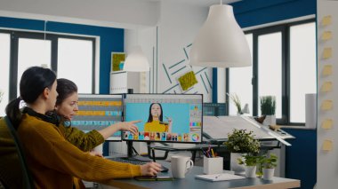 Kendine güvenen kadın fotoğraf editörleri yaratıcı iş yerinde oturmuş fotoğrafları rötuşluyorlar.