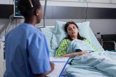 Siyahi Afro-Amerikan asistanı hastaların hastalık semptomlarını izlemesini tartışıyor.