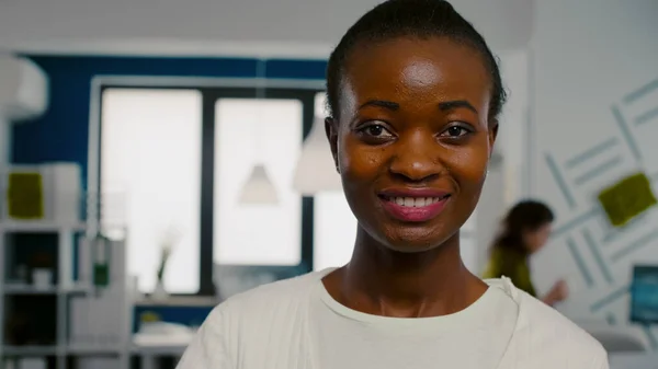 Mulher africana olhando para a câmera sorrindo em pé na start up agência criativa — Fotografia de Stock