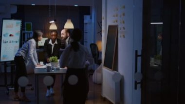 Konferans masasında durmuş yönetim grafiklerini analiz eden çok ırklı iş adamları takım çalışması