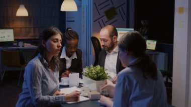 Konferans masasında oturan çok ırklı girişimciler, şirketin çözüm sunumunda fazla çalışıyorlar