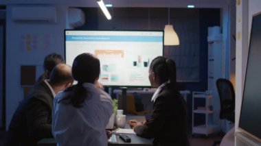 İş kadını, ofiste aşırı çalışan sunum monitörü kullanarak finansal grafikleri açıklıyor