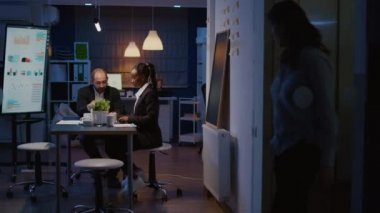 Çok ırklı iş adamları ofis toplantı odasında fazla mesai yapıyor.