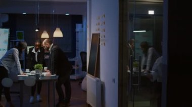 Çok ırklı iş adamları konferans masasına yaslanarak şirketin strateji fikirlerini analiz ediyorlar