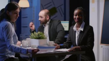 Toplantı odasında konferans masasında oturan odaklanmış gülümseyen Afrikalı Amerikalı kadının portresi.