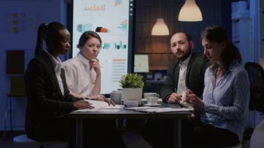 Çeşitli etnik çeşitlilikteki iş adamları konferans masasında oturmuş şirket stratejisini tartışıyorlar.