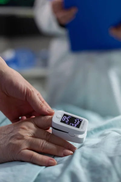 A kórházi ágyon fekvő betegen elhelyezett oxigénmérő közelsége — Stock Fotó