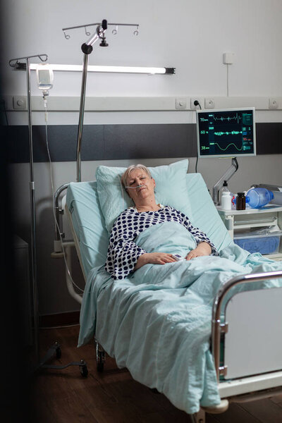 Elderly patient following recovery treatment laying in hospital bed
