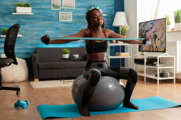 Atletica in forma gioiosa donna nera che lavora fuori muscolo posteriore con elastico — Foto Stock