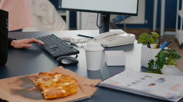 Closeup van zakenvrouw zitten aan het bureau in de voorkant van computer eten pizza slice — Stockfoto