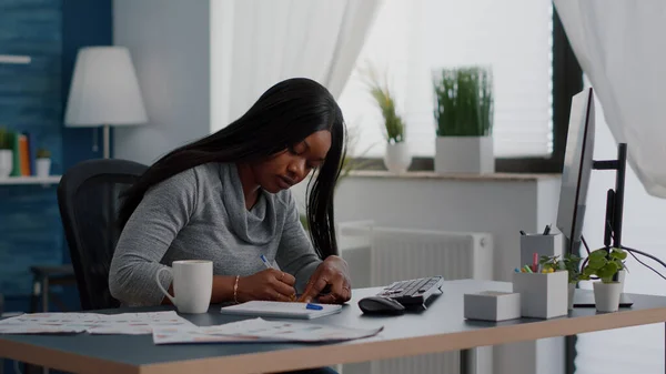 Estudiante negro escribiendo ideas de educación en notas adhesivas sentado en la mesa del escritorio en la sala de estar —  Fotos de Stock