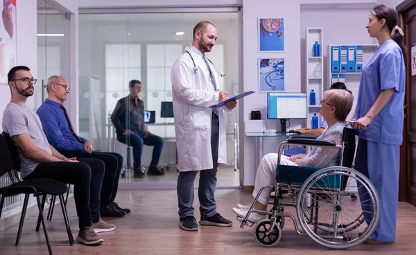 Médico hablando con mujer discapacitada en la sala de espera del hospital — Foto de Stock