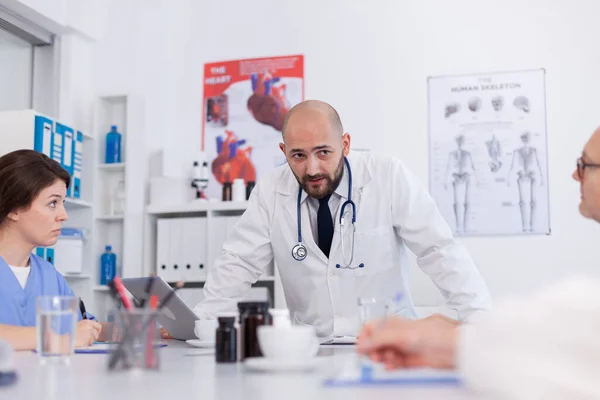 Radiólogo médico hombre explicando el tratamiento médico al trabajo en equipo médico mientras está de pie en el escritorio — Foto de Stock