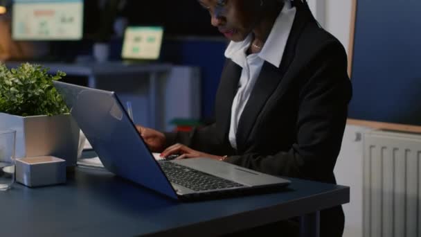 Femme d'affaires afro-américaine écrivant des statistiques d'entreprise sur ordinateur portable — Video