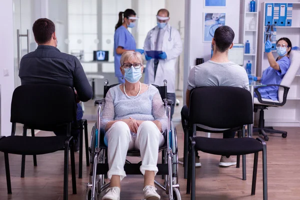 Worried disabled old woman sitting in wheelchair in hospital looking at camera — Stock Photo, Image