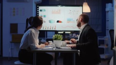 Monitörde yönetim stratejisi sunumuna bakan çeşitli iş adamları grubu