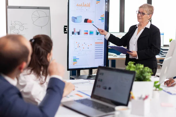 Gerente de proyecto de edad avanzada apuntando al escritorio presentando datos estadísticos — Foto de Stock