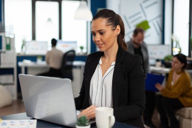 Hevesli kadın yönetici internette dizüstü bilgisayar kullanarak geziniyor.