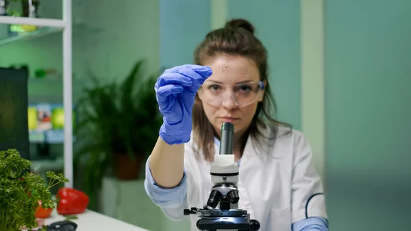 Científico bioquímico analizando muestras líquidas verdes usando microscopio — Foto de Stock