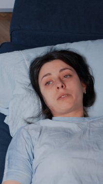 Üzgün, genç bir kadın, yalnız başına kanepede oturup ağlıyor.