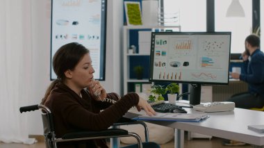 Tekerlekli sandalyede hareketsiz oturan finans uzmanı telefonda konuşuyor.