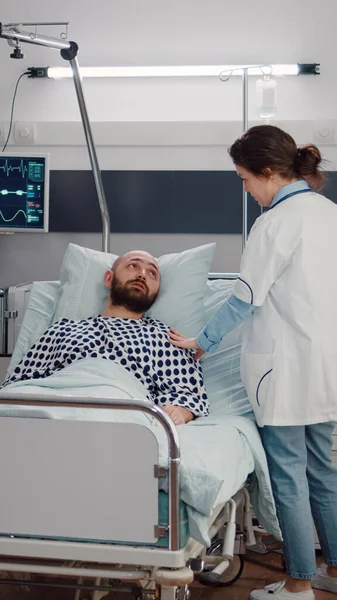 Uomo malato che riposa a letto mentre il medico terapeuta controlla il recupero respiratorio — Foto Stock