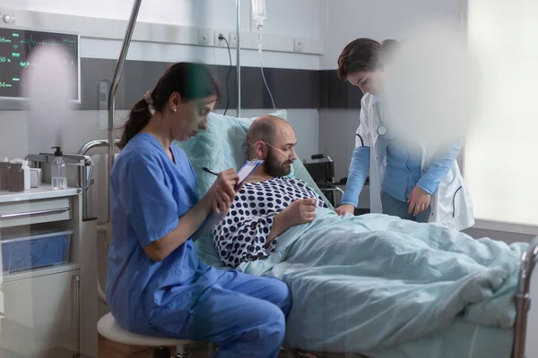 Malade patient au lit discutant avec une infirmière médicale expliquant le symptôme de la maladie — Photo