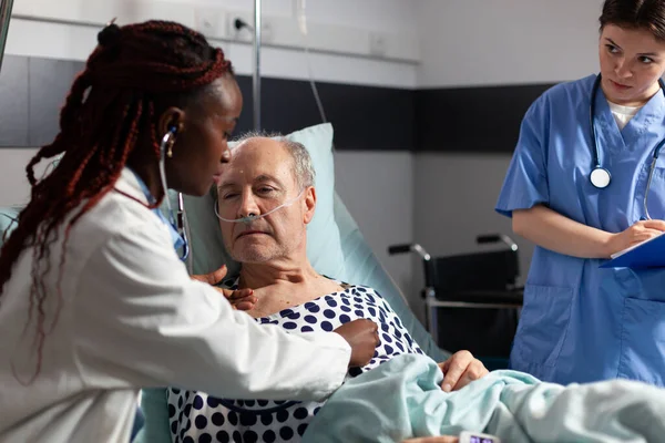 Afrikanischer Kardiologe untersucht Herz eines älteren Patienten — Stockfoto