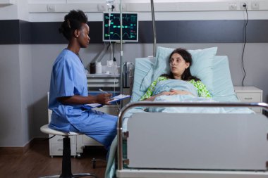 Siyahi hemşire hasta teşhisini panoya yazıyor.