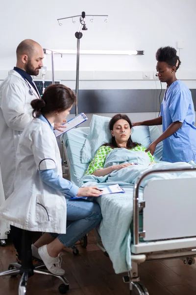 Medisch team toezicht zieke patiënt tijdens herstel afspraak in ziekenhuis afdeling. — Stockfoto