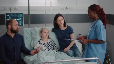 Siyahi cilt danışmanı bir kız hastayla çocuk doktoru asistanı hastalık belirtilerini tartışıyor.