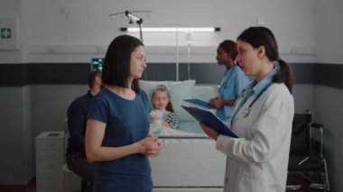 Anne, hastalık muayenesi sırasında çocuk doktoruyla tıbbi tedaviyi tartışıyor.